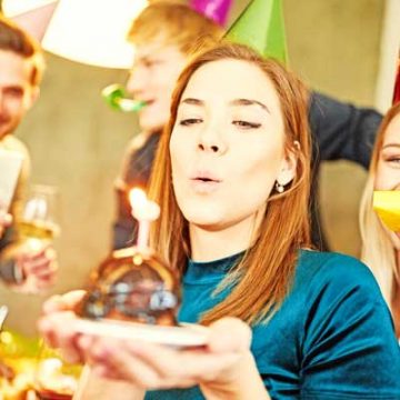 Woman blows out cake on birthday party and is photographed for Foodblog